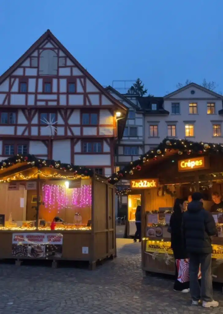 Christmas market food stalls including crepes stand in front of half-timbered St. Gallen buildings