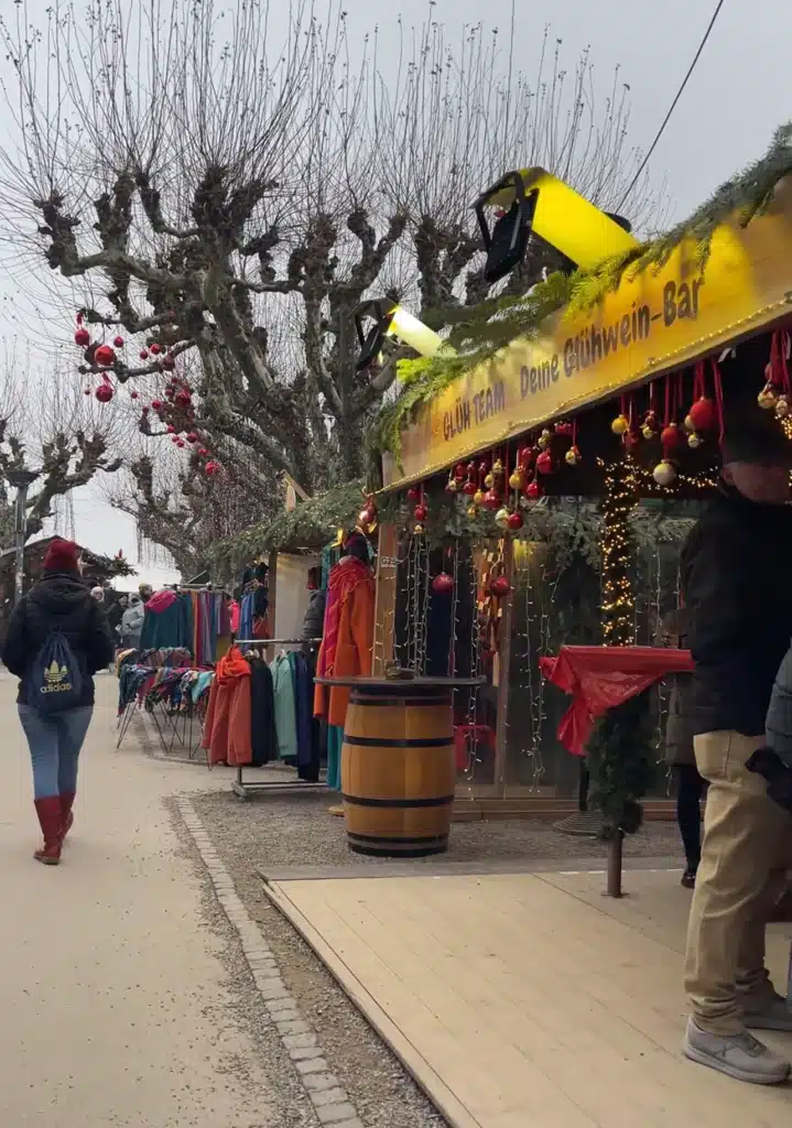 Glühwein bar stall and clothing racks lining a pathway at Konstanz Christmas Market