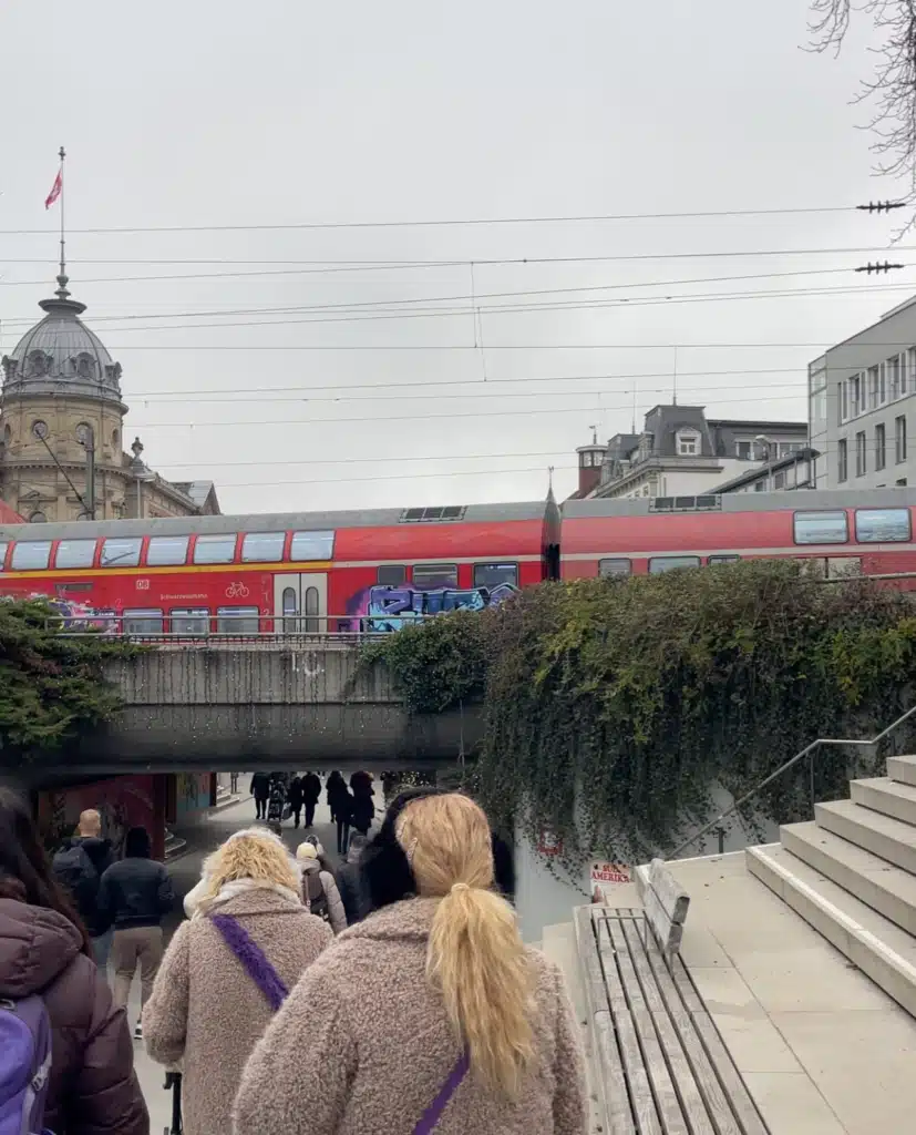 Red regional train crossing bridge above pedestrian underpass near Konstanz train station