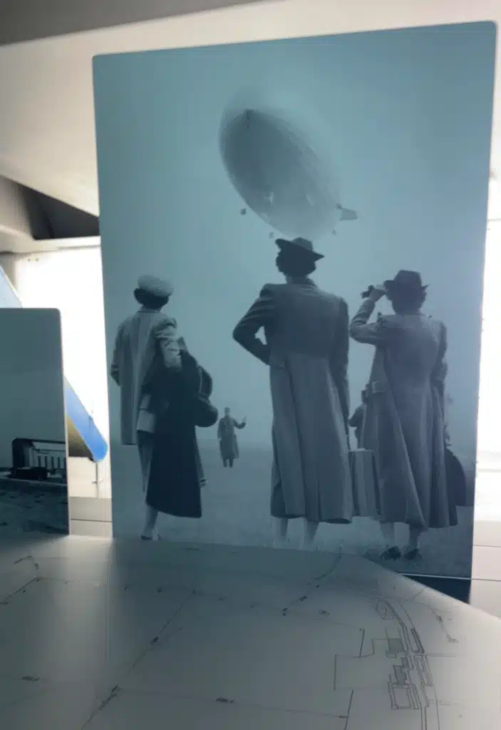 Backlit historic photo of 1930s travelers watching an airship overhead, Zeppelin Museum Friedrichshafen