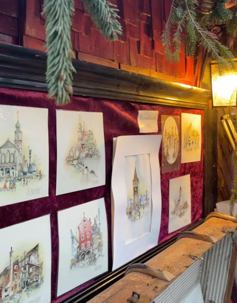Watercolour art prints of Lindau landmarks displayed on red velvet at a Christmas market stall