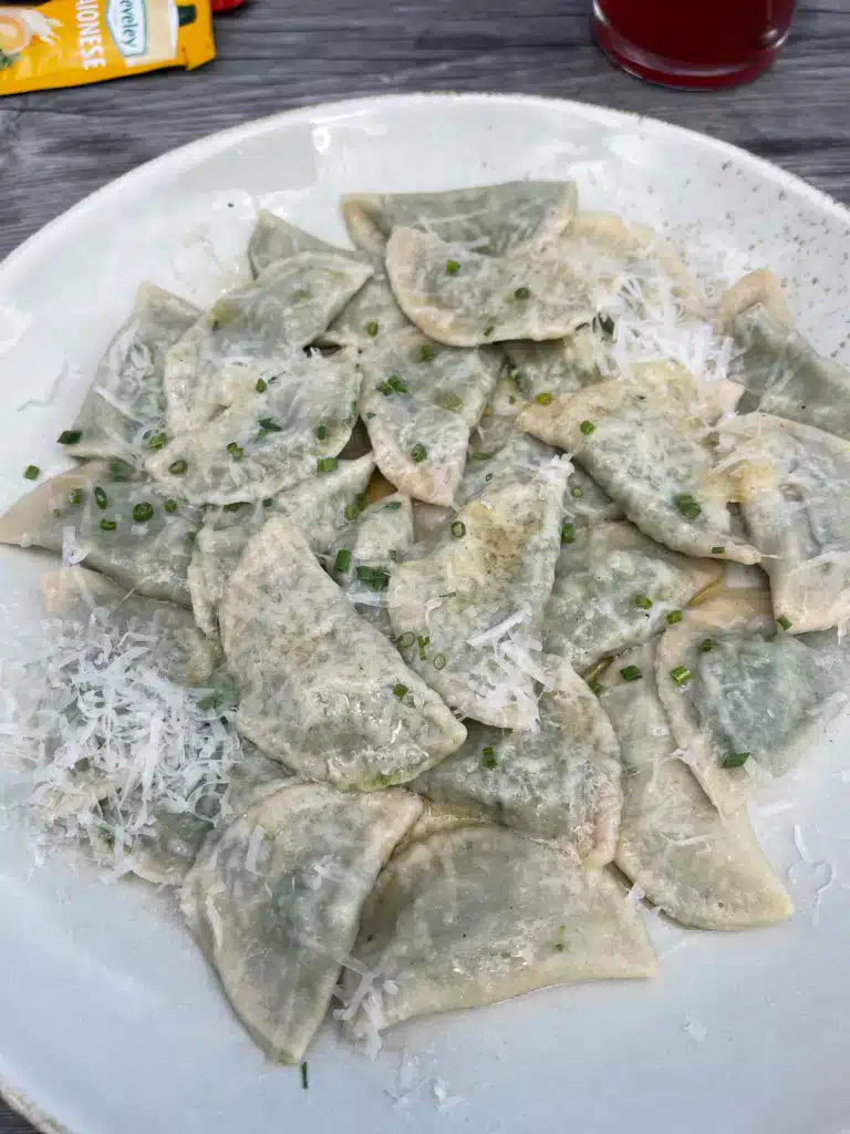 Plate of spinach dumplings topped with grated parmesan and chives at Ütia Vaciara mountain hut