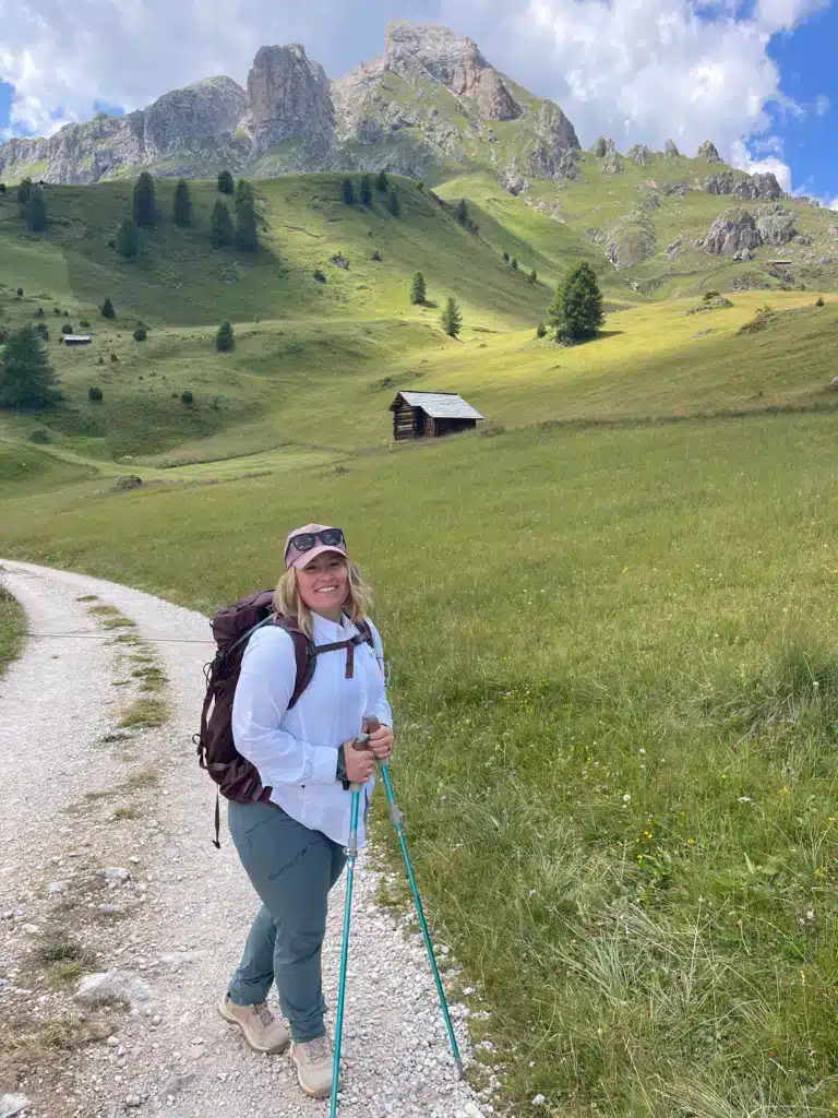 Smiling hiker with trekking poles in front of the Sass de Putia rock tower