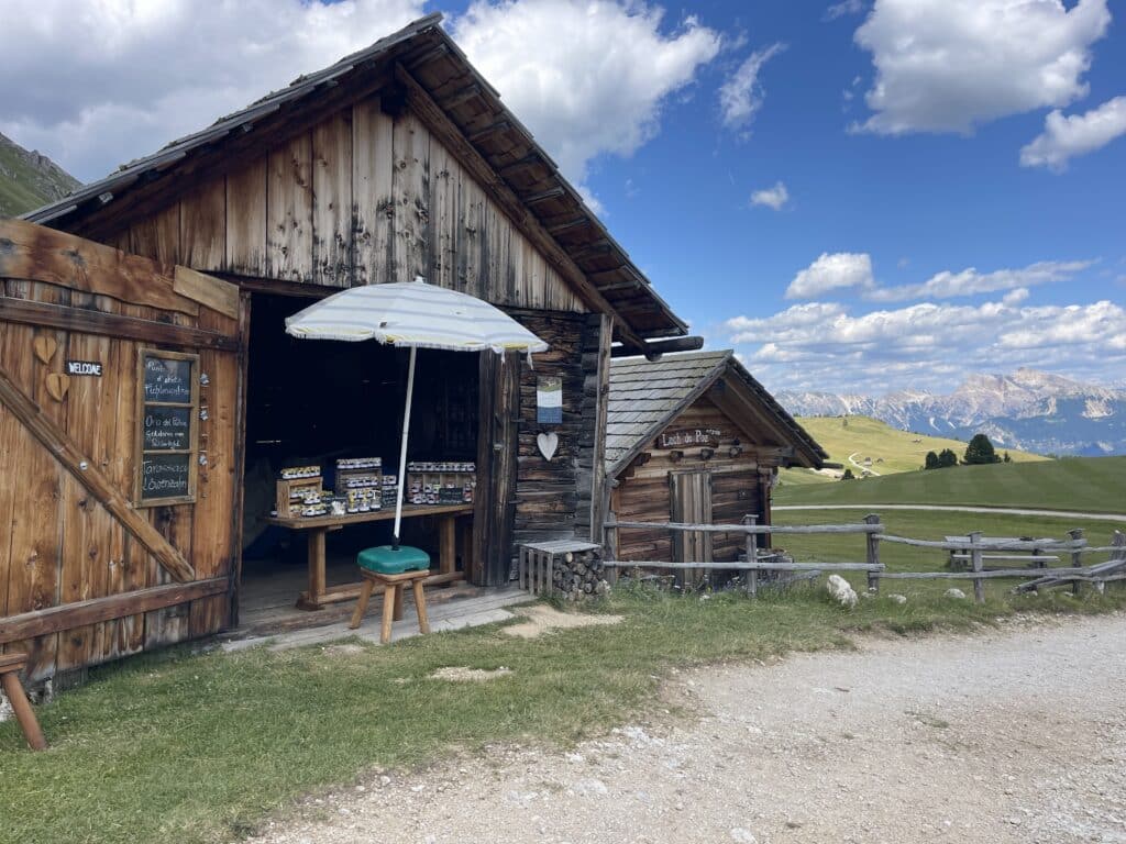 Rustic wooden Lech de Poz hut with a striped umbrella and a table of local honey and jam products for sale
