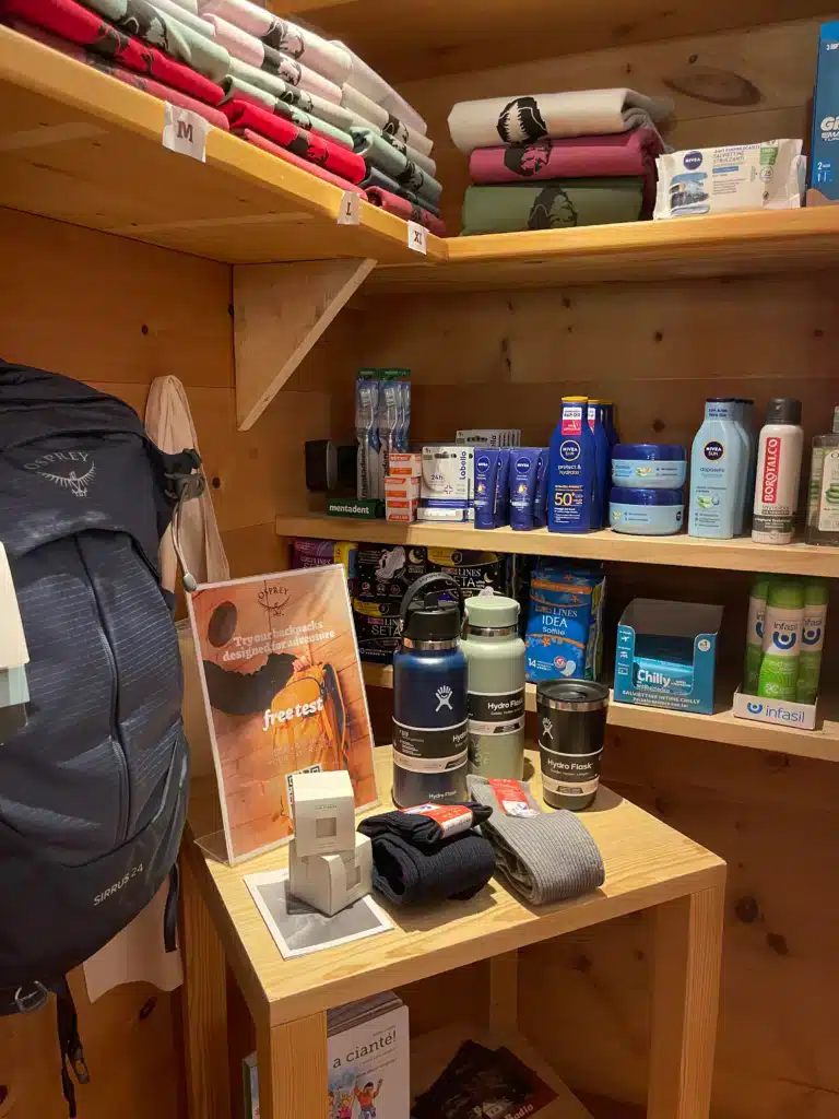 Convenience corner at Ütia de Börz stocked with Osprey backpacks, Hydro Flasks, and toiletries