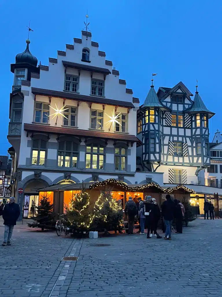 Historic St. Gallen square with illuminated star decorations and Christmas market stall at dusk