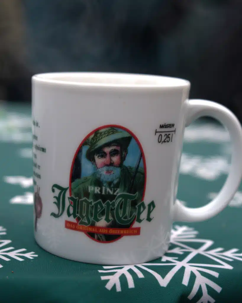 A steaming Prinz Jagertee mug on a snowflake tablecloth at the Lindau Christmas market