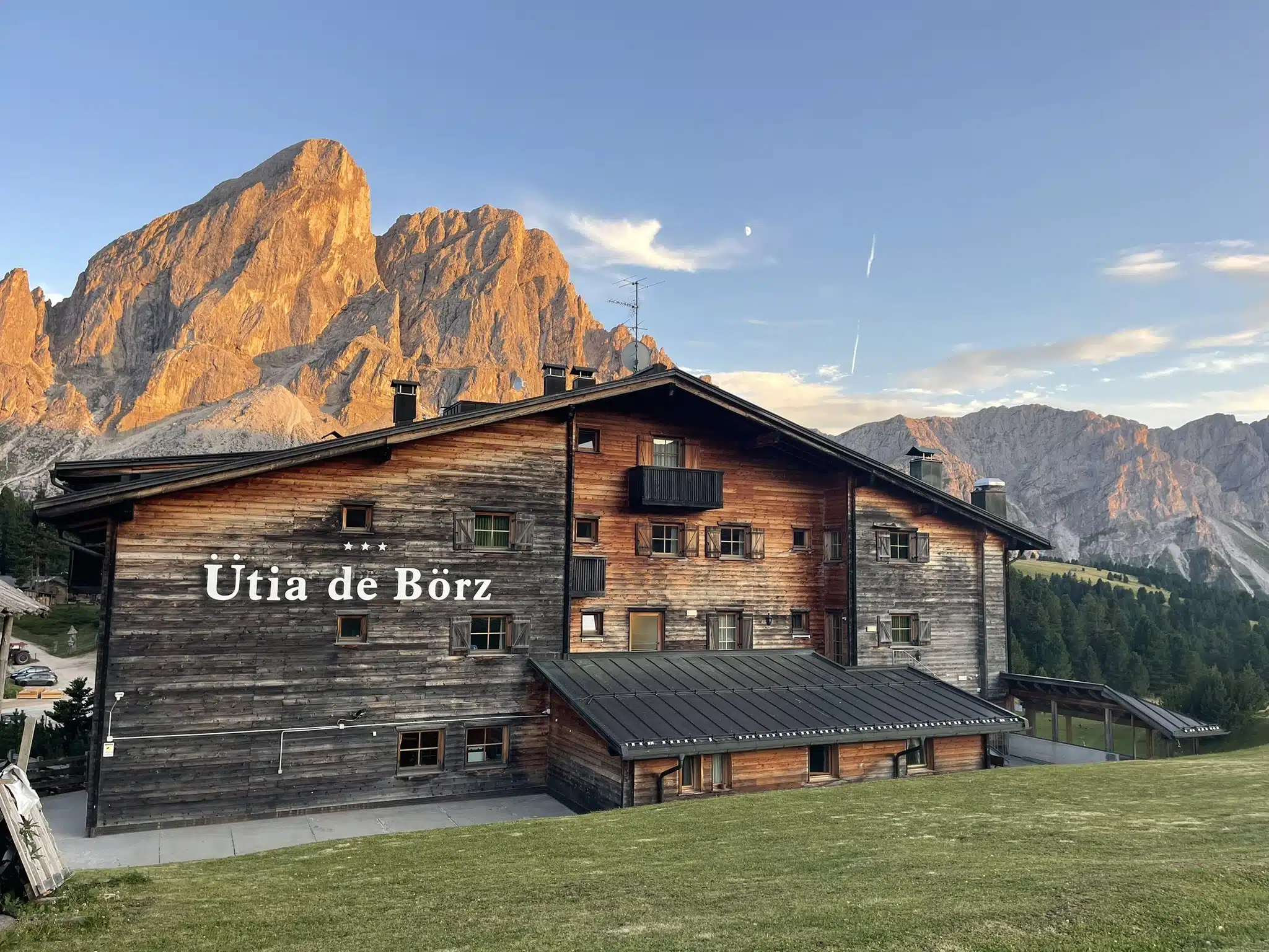 Ütia de Börz hotel exterior at golden hour with Sass de Putia peak glowing behind it in the Dolomites