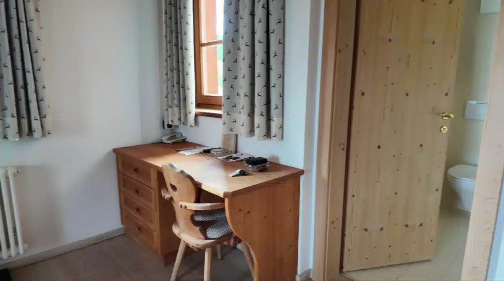 Wooden desk with chair by the window, next to the open bathroom door, at Ütia de Börz