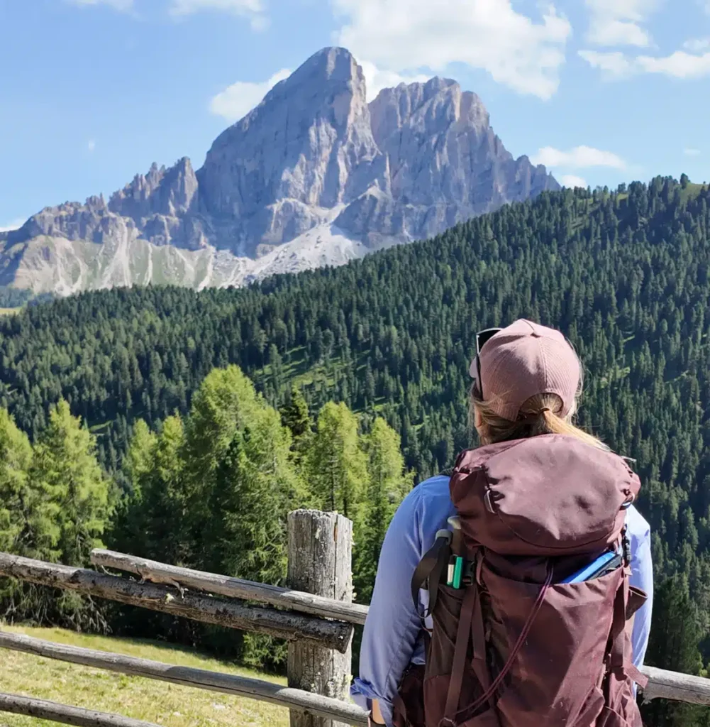 Hiker viewed from behind admiring Sass de Putia from the trail
