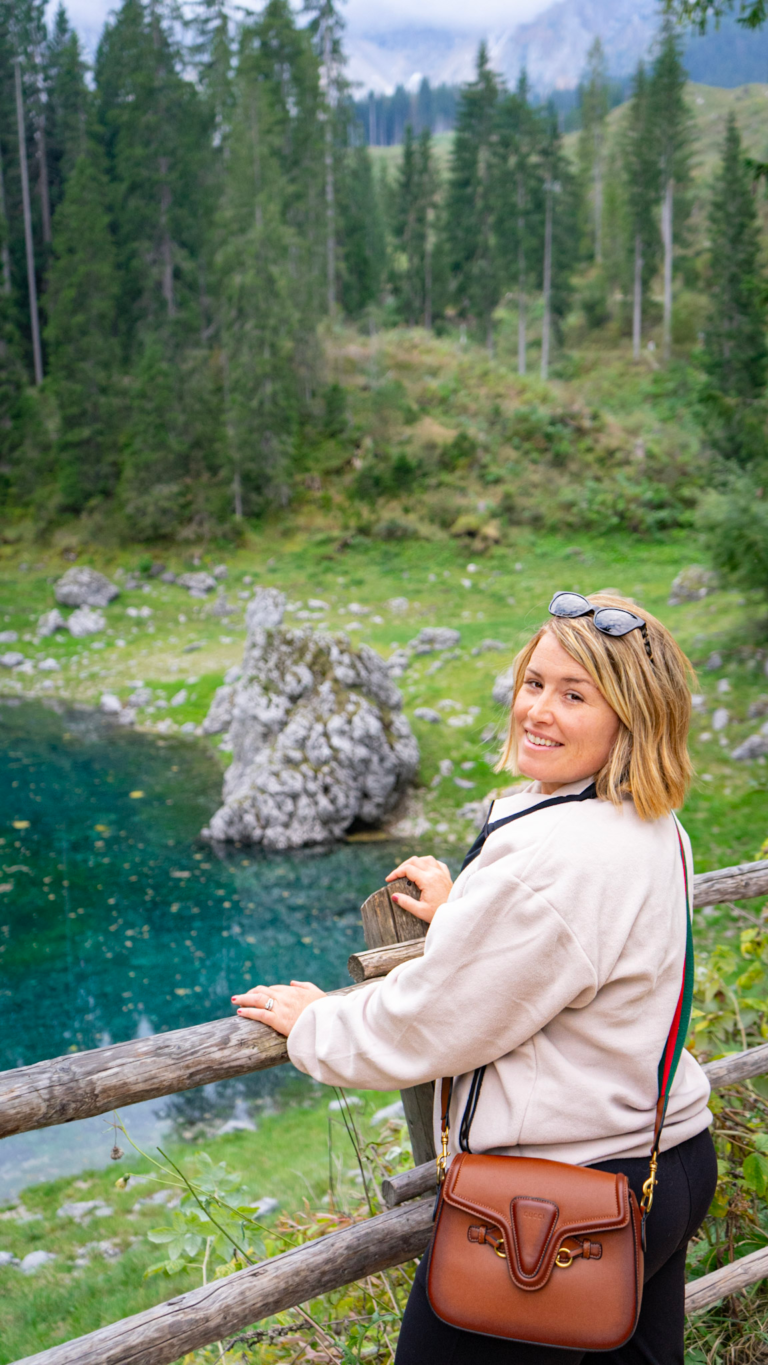 Kimberly at the wooden fence above Lago di Carezza, looking out over turquoise water and the rock spire