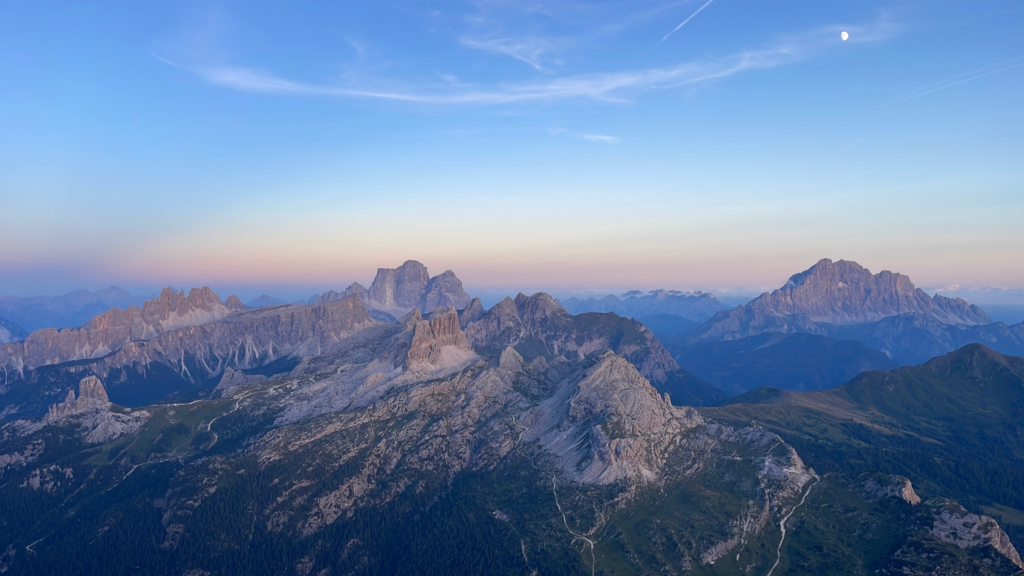 Panoramic view of the Dolomites at dusk with the moon rising over the peaks