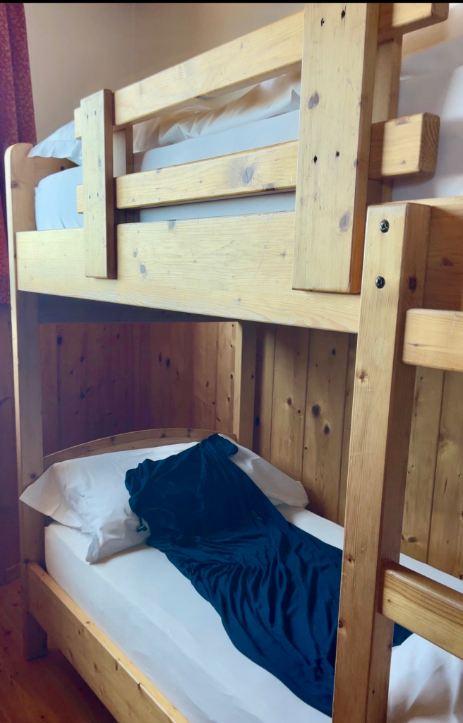 Close-up of a bunk bed with a dark teal blanket at Rifugio Lagazuoi