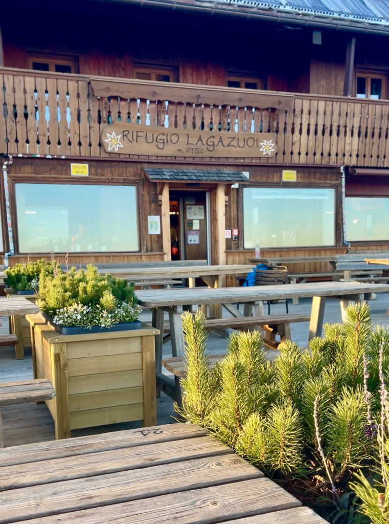 Rifugio Lagazuoi exterior terrace with picnic tables and potted alpine plants in evening light