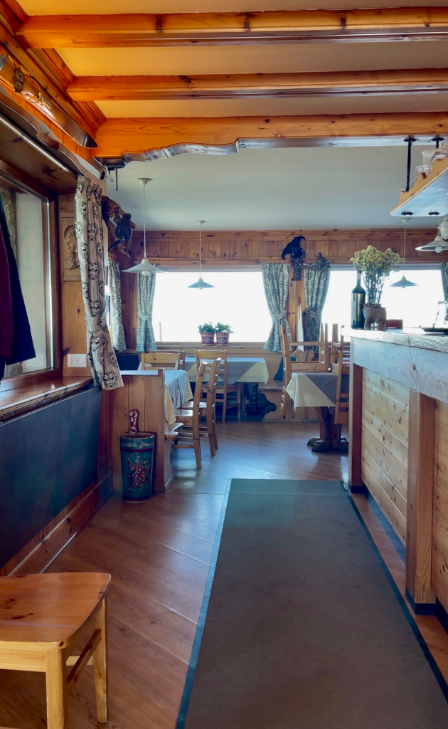 Wood-paneled dining room at Rifugio Lagazuoi with set tables and mountain-lodge decor