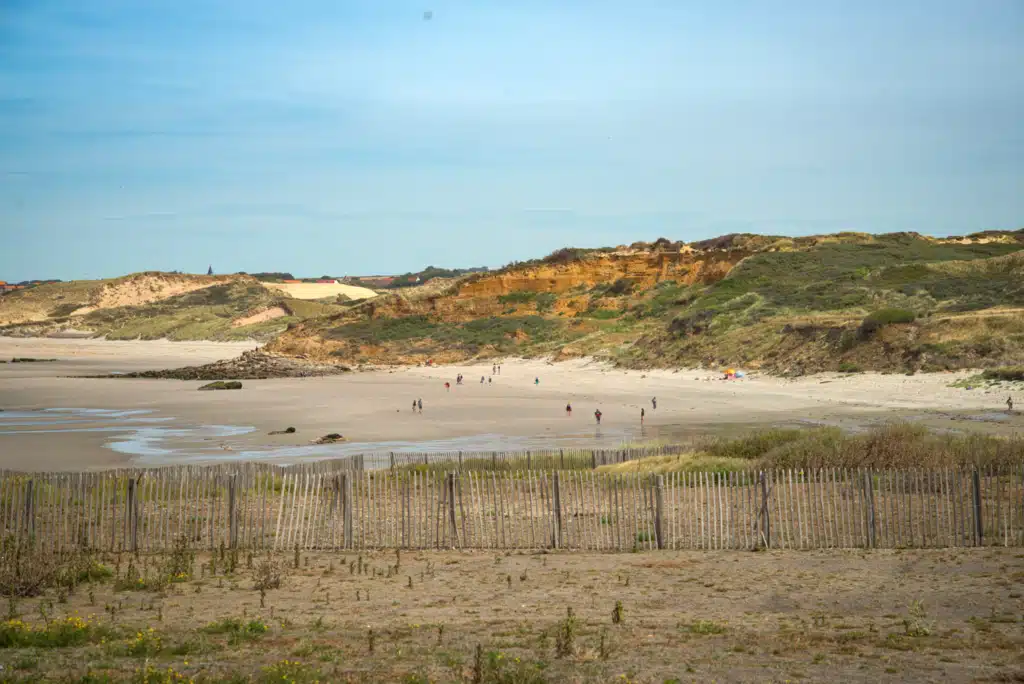 A sandy beach on the Cote d'Opale on frances northern coast where beachgoers are walking along the shore on a sunny day