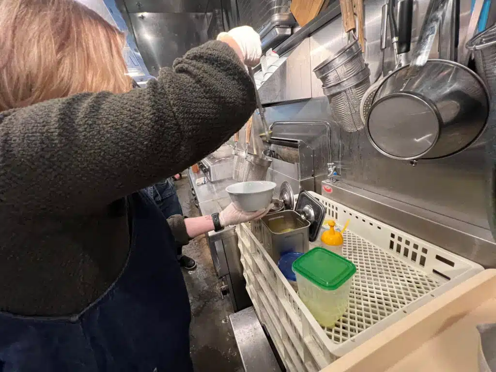 Boiling ramen noodles in a basket at the kitchen line during an Osaka ramen cooking class