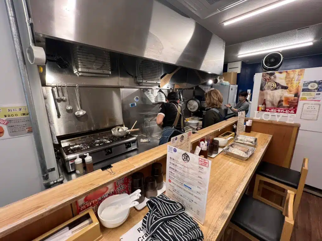 Chef Shu guiding a student at the kitchen line during a ramen cooking class in Osaka