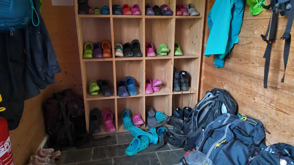 Boot room at Refuge du Col du Palet with communal crocs, hiking boots and backpacks, Tour du Vallaisonnay hut-to-hut trek in Vanoise National Park