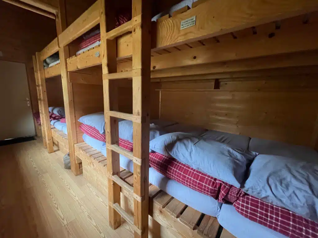 Shared dormitory with wooden bunks and blankets at Refuge du Col du Palet, hut-to-hut accommodation on the Tour du Vallaisonnay in Vanoise National Park