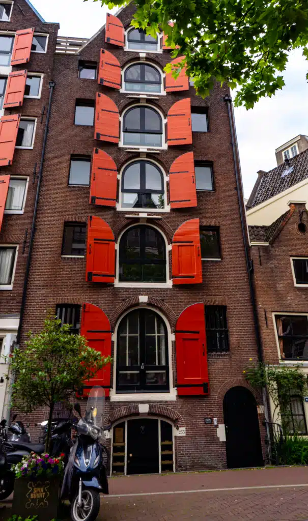 Tall narrow Amsterdam canal house with bright orange shutters in the Spui neighborhood