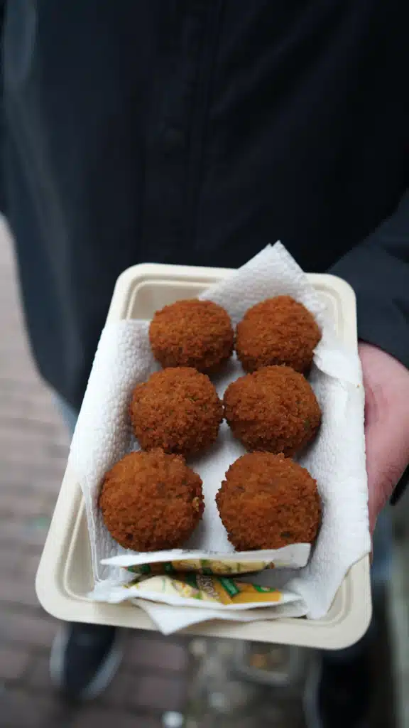 Six fried bitterballen served in a paper tray with mustard on an Amsterdam food tour