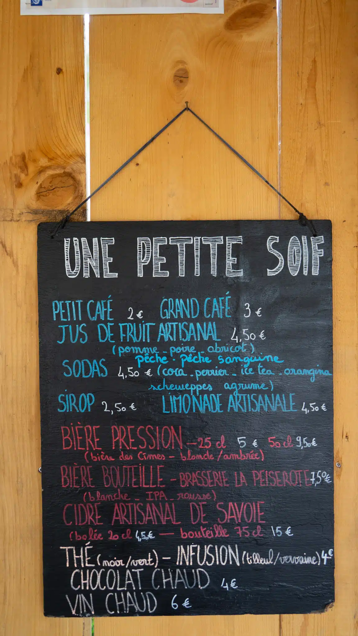 a handwritten menu in french at Entre Le Lac describing how much drinks run at the refuge