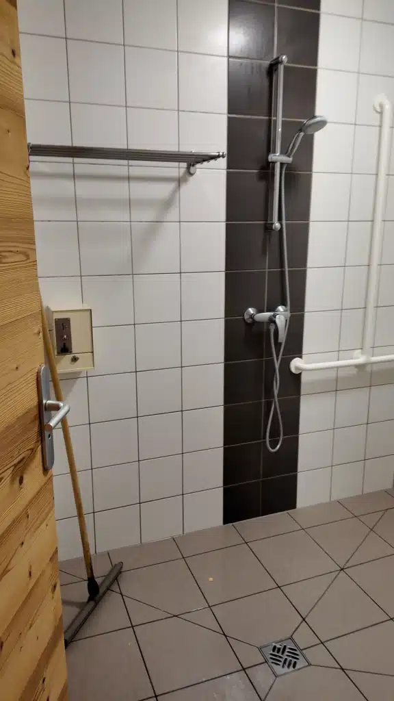 Tiled shower room at Refuge de la Glière with a coin-operated timer box, hut-to-hut bathroom facilities on the Tour du Vallaisonnay
